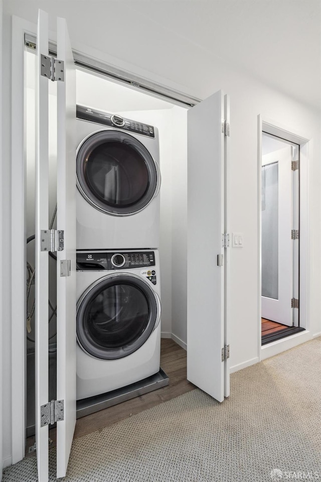 washroom featuring stacked washer and dryer and carpet floors