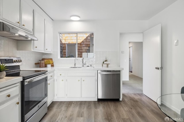 kitchen with stainless steel appliances, sink, white cabinets, and light hardwood / wood-style floors