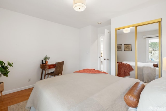 bedroom with a closet, baseboards, and wood finished floors