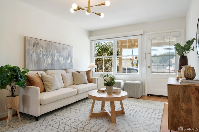 living room with a chandelier, light wood finished floors, and a healthy amount of sunlight