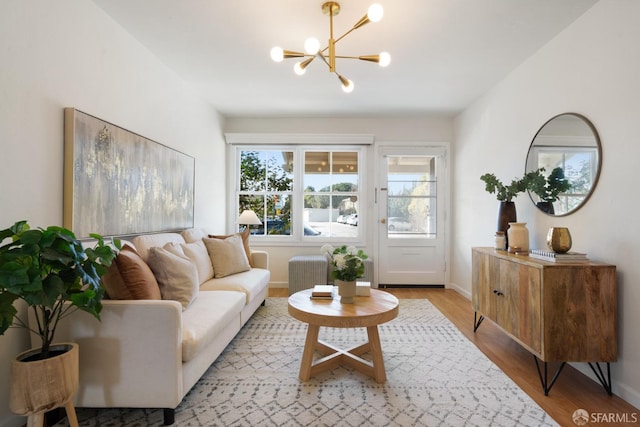 living area featuring light wood-style floors, baseboards, and an inviting chandelier