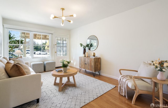 living area with an inviting chandelier, baseboards, and wood finished floors