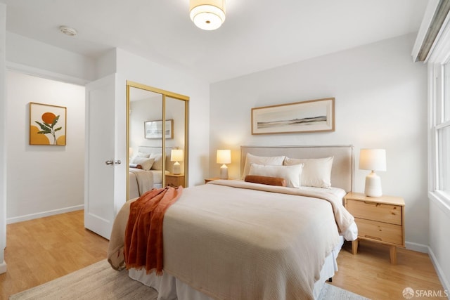 bedroom featuring a closet, light wood-type flooring, and baseboards