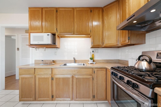 kitchen with light countertops, white microwave, a sink, stainless steel gas range oven, and exhaust hood