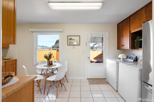 kitchen featuring light countertops, washing machine and clothes dryer, a wealth of natural light, and brown cabinets