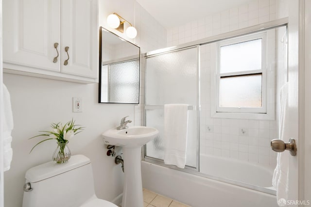 full bath with combined bath / shower with glass door, tile patterned flooring, and toilet