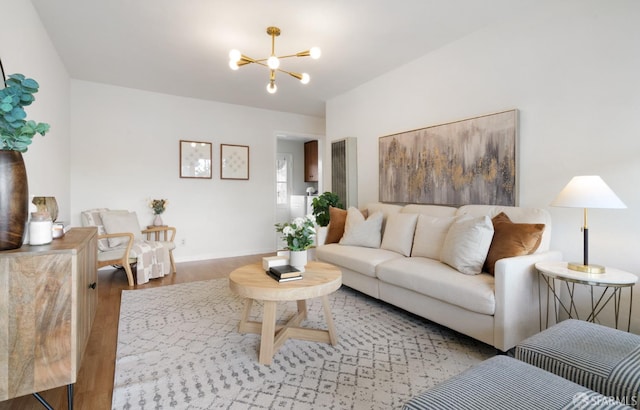 living area featuring a chandelier, baseboards, and light wood finished floors