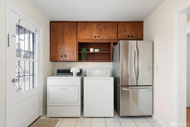 clothes washing area featuring light tile patterned floors, cabinet space, baseboards, and separate washer and dryer