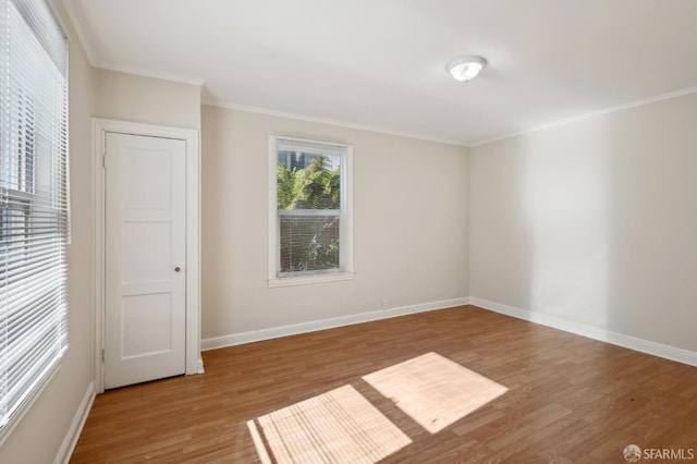 spare room featuring wood-type flooring and crown molding