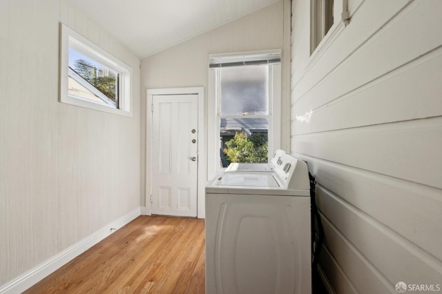 clothes washing area featuring a healthy amount of sunlight, washer and clothes dryer, and light wood-type flooring