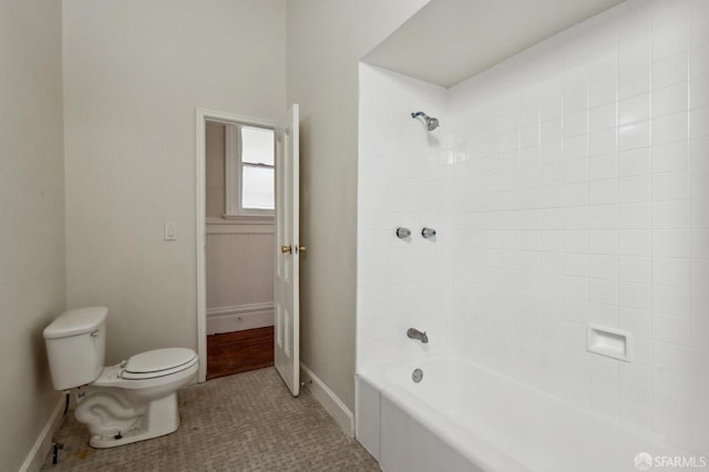 bathroom featuring tiled shower / bath, tile patterned floors, and toilet