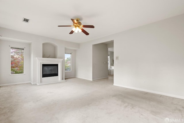 unfurnished living room featuring light colored carpet, plenty of natural light, and ceiling fan