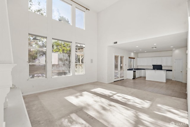 unfurnished living room with a towering ceiling and light tile patterned floors