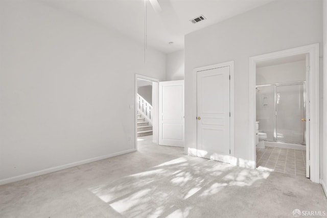 unfurnished bedroom with ensuite bathroom, ceiling fan, and light colored carpet