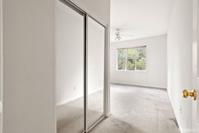 unfurnished bedroom with a closet, light colored carpet, and ceiling fan