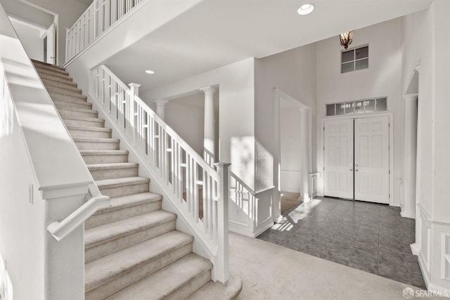 carpeted foyer with ornate columns and a high ceiling