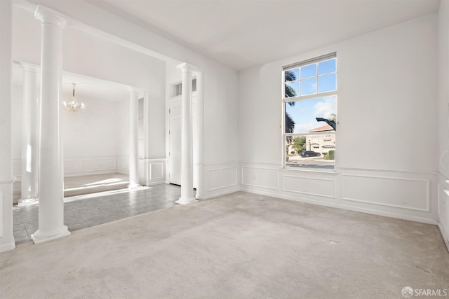 spare room with carpet, decorative columns, and a chandelier