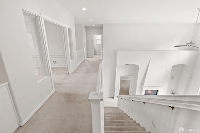 stairs with carpet, a fireplace, and ceiling fan