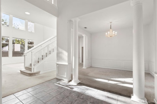 staircase with decorative columns, carpet, a high ceiling, and an inviting chandelier