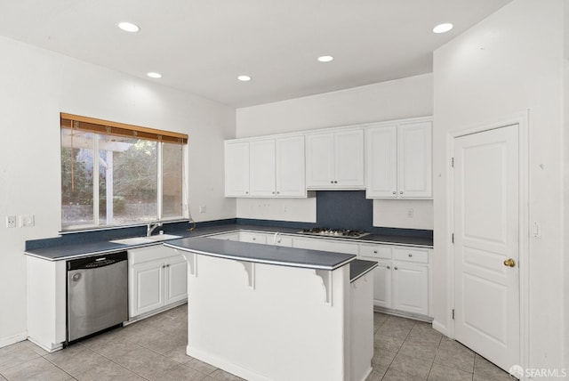 kitchen featuring a kitchen bar, stainless steel appliances, sink, light tile patterned floors, and white cabinetry