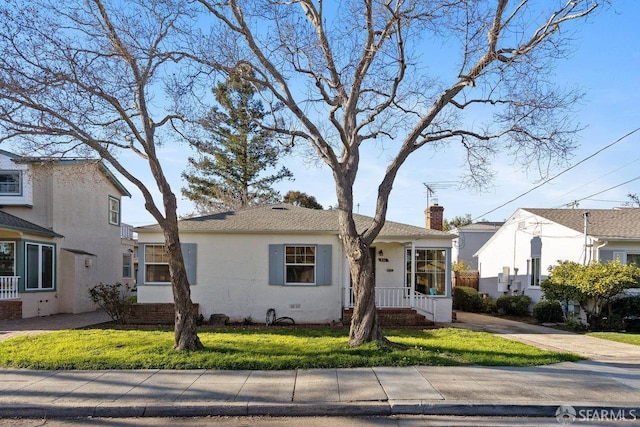 view of front facade with a front yard, crawl space, a chimney, and stucco siding