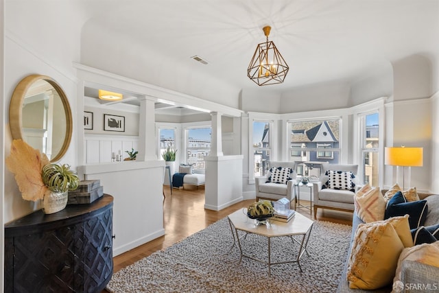 living room featuring a chandelier, light hardwood / wood-style flooring, and ornate columns