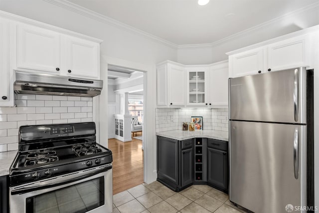 kitchen featuring crown molding, light stone countertops, appliances with stainless steel finishes, white cabinetry, and light tile patterned floors