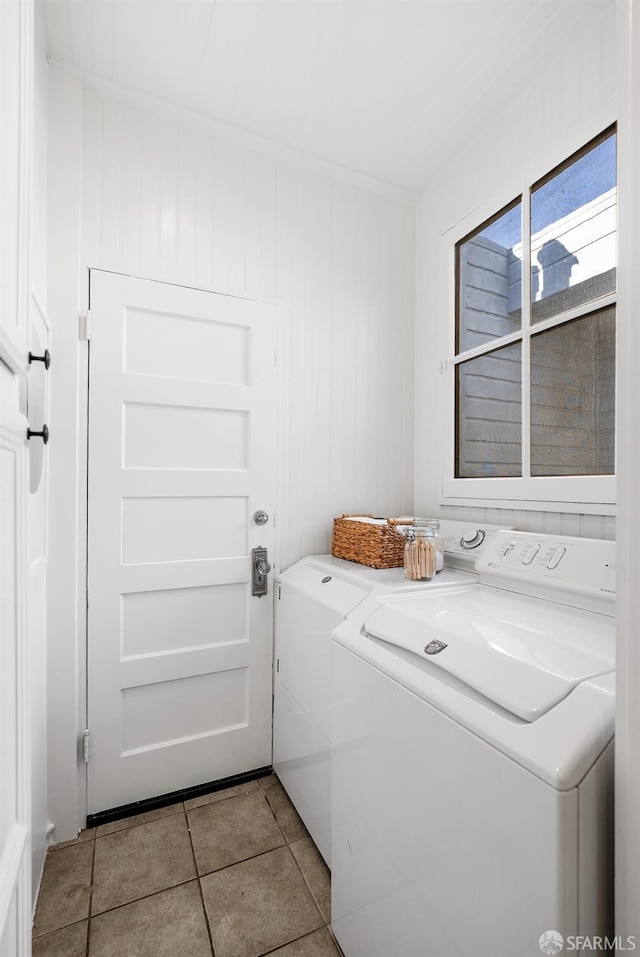 laundry area with wood walls, washing machine and dryer, and light tile patterned floors