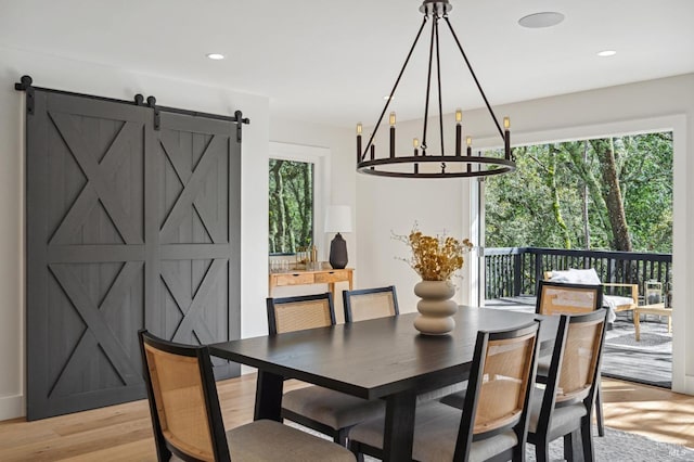 dining room with a barn door, light hardwood / wood-style floors, and an inviting chandelier