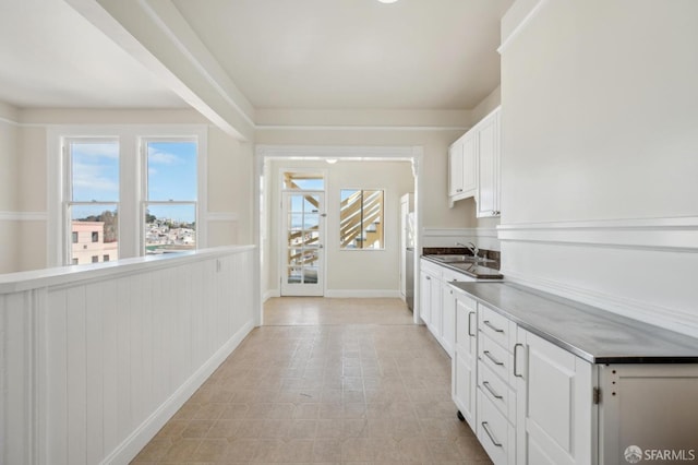 kitchen featuring white cabinets, light floors, and a sink