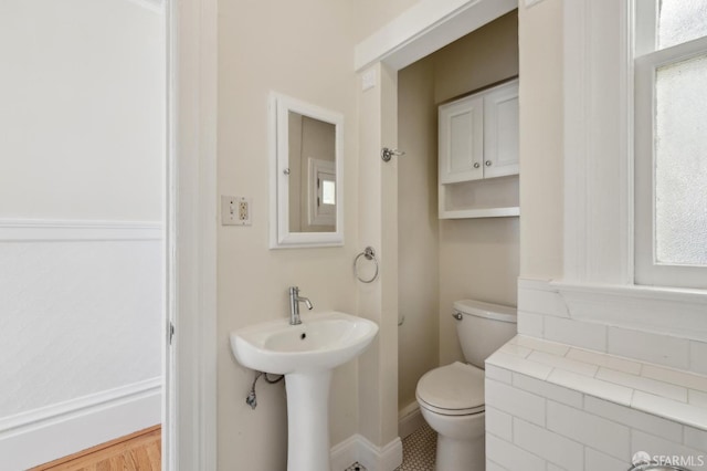 bathroom with a sink, baseboards, plenty of natural light, and toilet