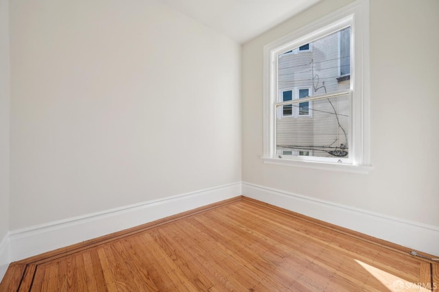 spare room featuring baseboards and wood finished floors