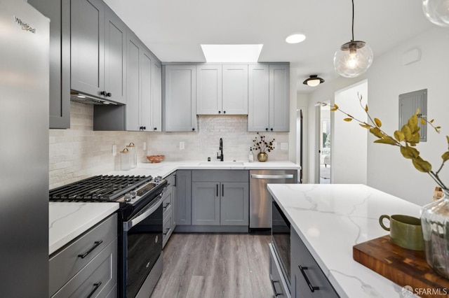 363 Prague St, San Francisco, CA 94112 - kitchen with stainless steel appliances, gray cabinetry, decorative backsplash, light wood finished floors, and light stone counters