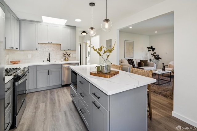 363 Prague St, San Francisco, CA 94112 - kitchen with gray cabinetry, range with gas cooktop, dishwasher, light wood-style flooring, and a kitchen island
