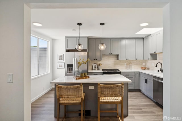 363 Prague St, San Francisco, CA 94112 - kitchen featuring stainless steel appliances, gray cabinetry, backsplash, and light wood-style flooring