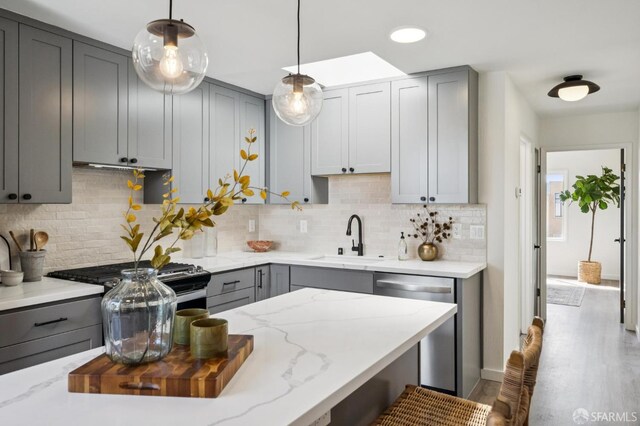 363 Prague St, San Francisco, CA 94112 - kitchen with gray cabinetry, stainless steel appliances, light stone counters, and decorative backsplash