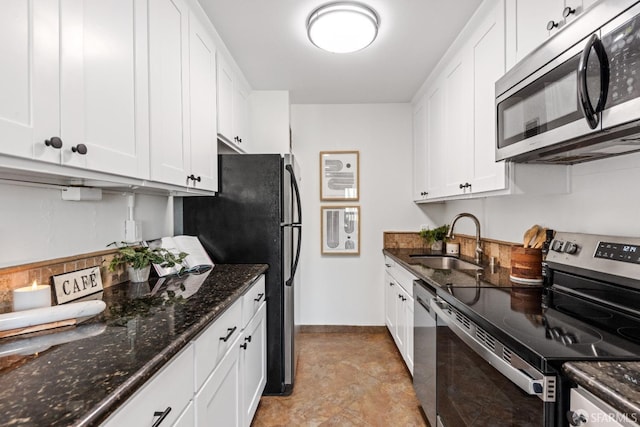 kitchen with white cabinets, stainless steel appliances, dark stone counters, and sink