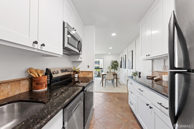 kitchen featuring dark stone counters, white cabinetry, light tile patterned floors, and stainless steel appliances