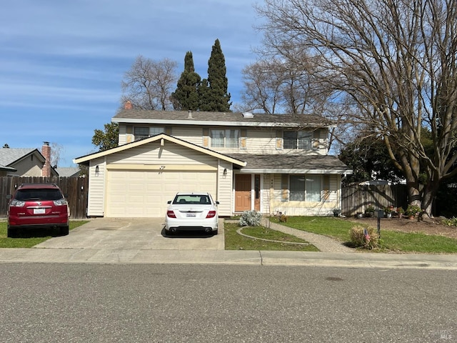 traditional-style house featuring an attached garage, fence, and concrete driveway