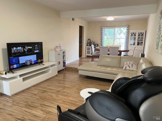 living room with light wood finished floors, baseboards, and beam ceiling