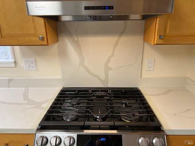 room details with tasteful backsplash, range hood, stainless steel gas range oven, and light stone countertops