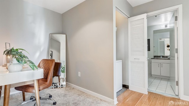 office with light wood finished floors, baseboards, and a sink