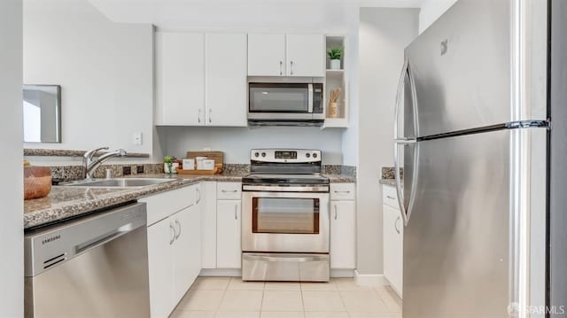 kitchen featuring light tile patterned floors, white cabinetry, appliances with stainless steel finishes, and a sink