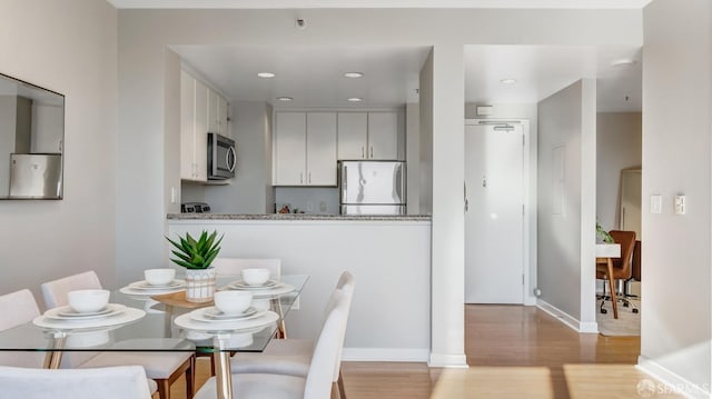 dining area with light wood-style flooring, baseboards, and recessed lighting