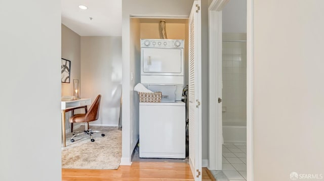 clothes washing area featuring laundry area, baseboards, stacked washer / dryer, and recessed lighting