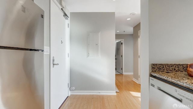 hallway with light wood-style flooring, recessed lighting, electric panel, and baseboards