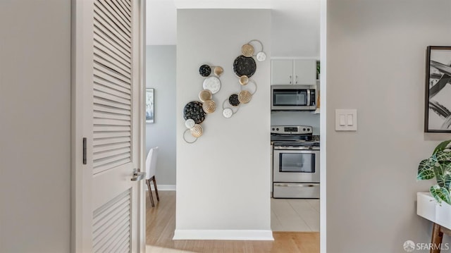 kitchen with stainless steel appliances, baseboards, and light wood-style floors