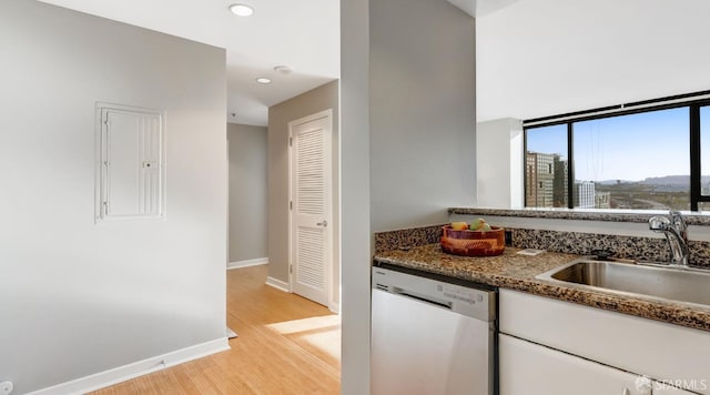 kitchen with electric panel, dishwasher, light wood-style flooring, white cabinetry, and a sink