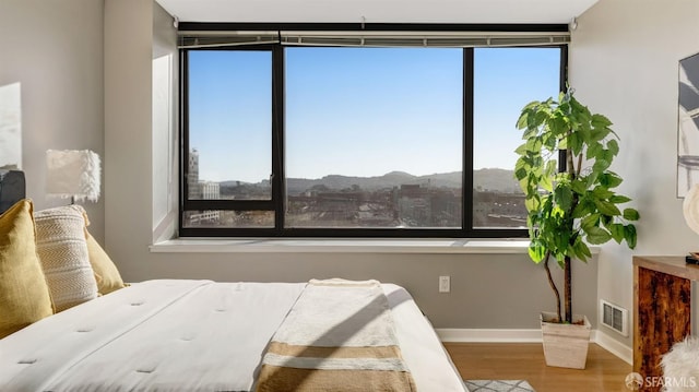 bedroom with baseboards, multiple windows, visible vents, and wood finished floors