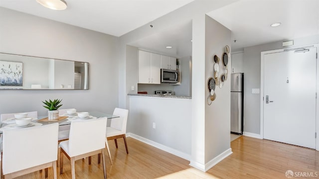 dining space featuring recessed lighting, light wood-style flooring, and baseboards